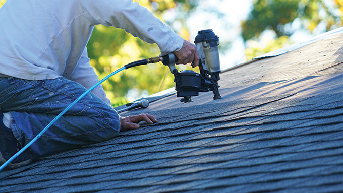 a person using a nail gun to affix roofing underlay onto a roof